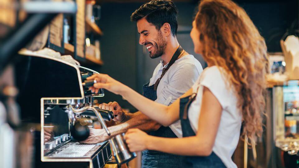 Glad barista der laver kaffe i en café 